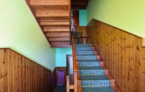 Eine Holztreppe mit gemustertem Teppich, die zu einem Raum mit grüner Wand führt.