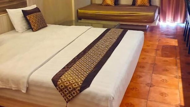 A hotel room with a large bed, a bedside table, a lamp, and a wall-mounted air conditioning unit.