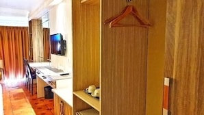 A hotel room with a kitchenette, a television, a wooden wardrobe, and a hanging coat rack.
