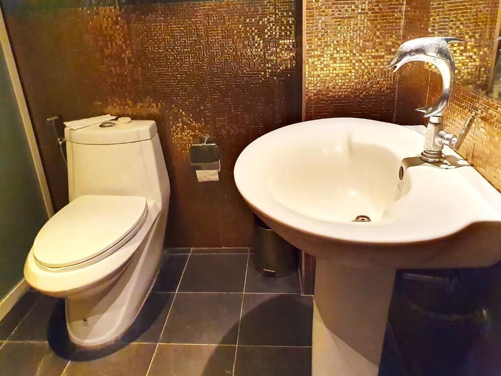 A bathroom with a toilet, sink, and tiled floor.