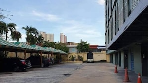 A parking area with multiple cars, a covered walkway, and a building with a metal facade.