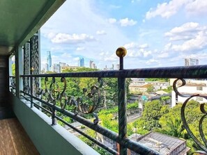 Un balcón con barandilla de metal que da a una vista urbana con edificios y zonas verdes.