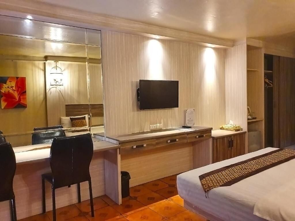 Una habitación de hotel con cama, escritorio, silla, televisor y armario.