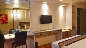 Una habitación de hotel con cama, escritorio, silla, televisor y armario.