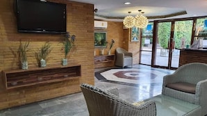 A lobby with a flat-screen TV, wicker furniture, a patterned floor, and a reception desk.