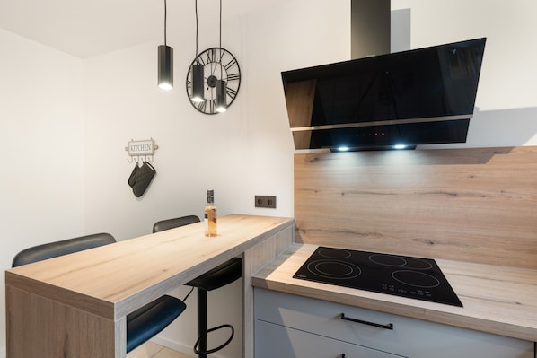 A modern kitchen with a wooden countertop, a built-in stove, and a wall-mounted clock.