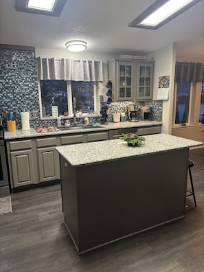 A modern kitchen with a central island, grey cabinets, and a window with a view. - Beautiful, cozy 3 bedroom, two bath, private home on acreage in the mountains (Lava Hot Springs)