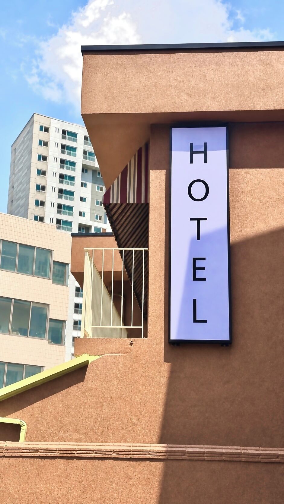 Letrero de hotel en un edificio de estilo arquitectónico moderno, con un cielo despejado y otros edificios al fondo.