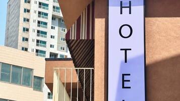 Letrero de hotel en un edificio de estilo arquitectónico moderno, con un cielo despejado y otros edificios al fondo.
