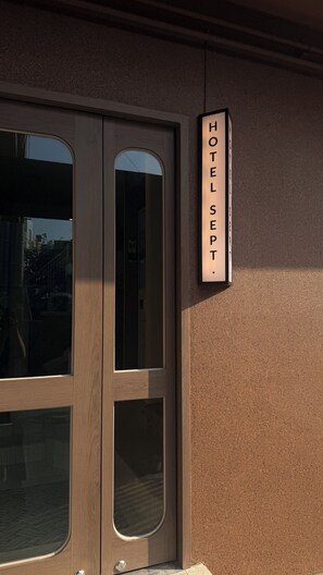Entrada de hotel con puerta de madera y un letrero que dice 'HOTEL SEPT'.