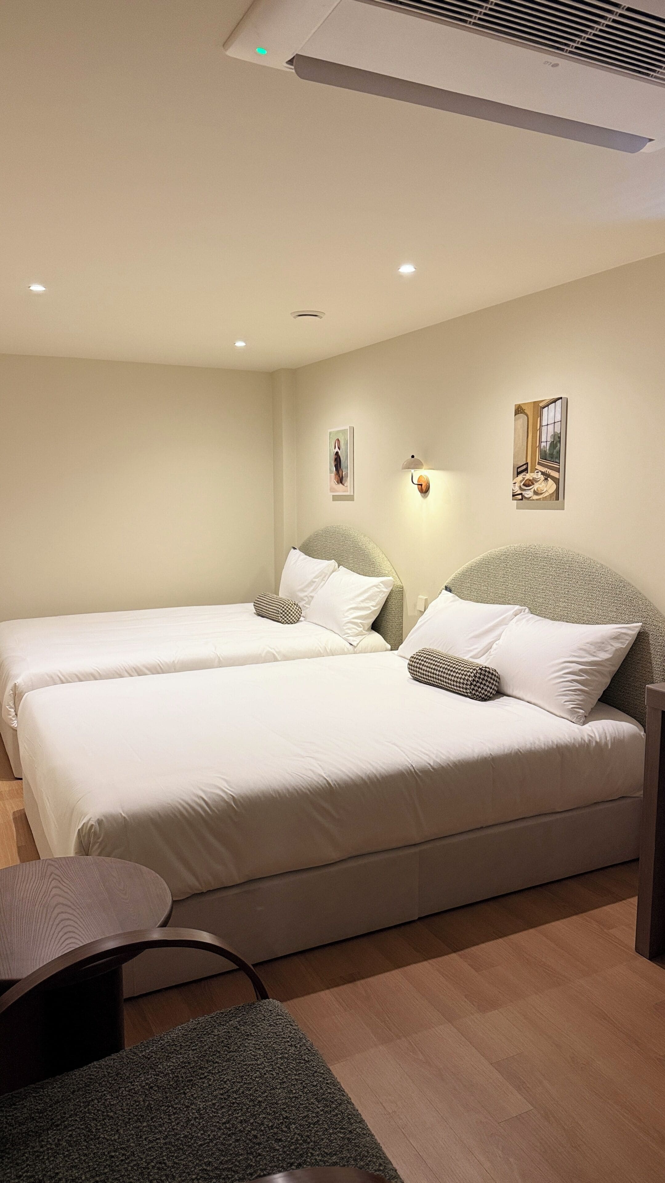 Una habitación de hotel con dos camas, una mesita y una silla.