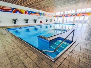 An indoor swimming pool with a tiled floor, a wooden ceiling, and colorful wall art. - Urban&Florian Top 101 by Interhome (Sankt Urban)