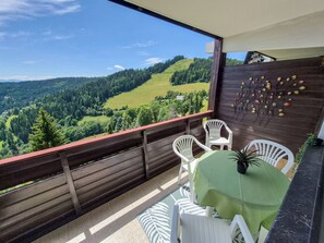 A balcony with a view of a forested valley, a wooden fence, and a table with chairs. - Urban&Florian Top 101 by Interhome (Sankt Urban)