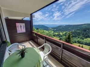 Een balkon met een tafel en stoelen, met uitzicht op een bergachtig landschap.
