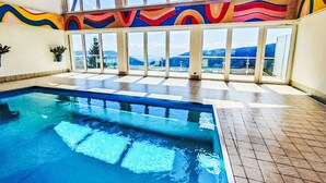 Une piscine intérieure avec de grandes baies vitrées donnant sur les montagnes.