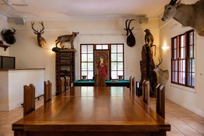 A dining room with a long wooden table, chairs, and a view of a window.