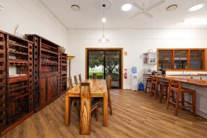 A dining area with a wooden table and chairs, a kitchen with wooden cabinets, and a ceiling fan.