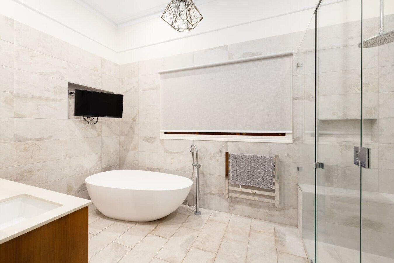 Un baño moderno con una bañera independiente, cabina de ducha con mampara de vidrio y tocador empotrado.