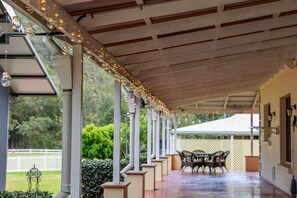 A covered outdoor area with a wooden ceiling, white columns, and a table with chairs.
