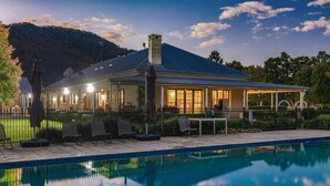 A poolside area with a covered patio, lounge chairs, and a view of a mountainous landscape.