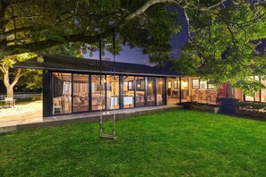 A modern house with a covered patio, large windows, and a well-maintained lawn.