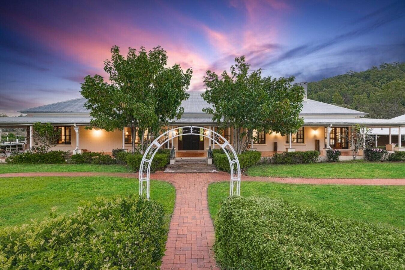 A two-story building with a central entrance archway, surrounded by well-maintained lawns and hedges.