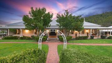 A two-story building with a central entrance archway, surrounded by well-maintained lawns and hedges.