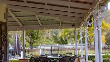 An outdoor patio with a table and chairs, string lights, and a view of a park.
