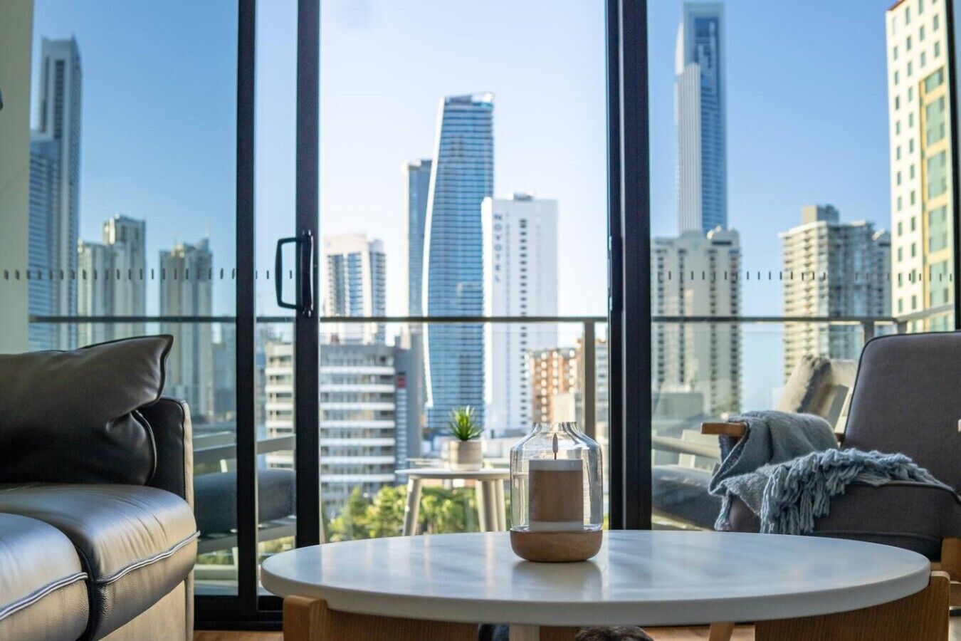 Een moderne woonkamer met uitzicht over de stad, een ronde tafel en twee leren banken.