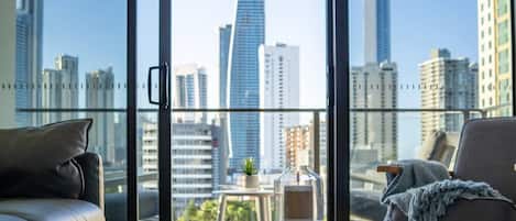 A modern living room with a city view, a round table, and two leather sofas.