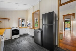 Eine Küche mit Herd, Backofen, Geschirrspüler und einem großen, schwarzen Kühlschrank.