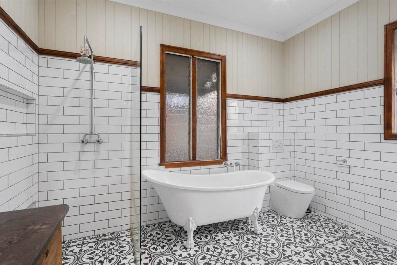 A bathroom with white subway tiles, a freestanding bathtub, a toilet, and a shower with a glass enclosure.