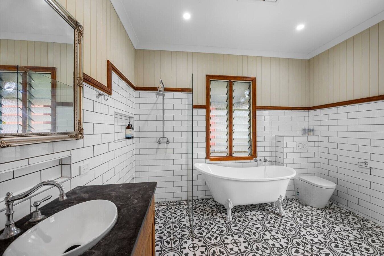 A bathroom with a freestanding bathtub, a toilet, and a sink with a mirror.