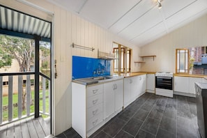 Una cocina con armarios blancos, un salpicadero azul, una estufa a gas y vistas al exterior.