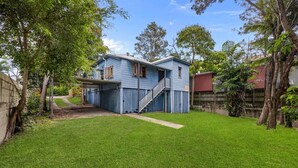 A residential property with a blue house, a covered porch, and a well-maintained lawn.