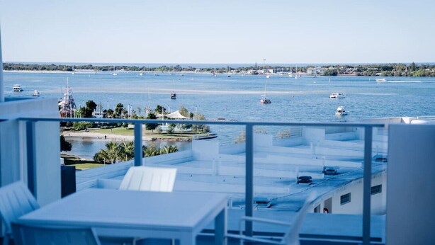 Un balcone con vista sul mare, barche e una costa in lontananza.
