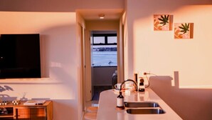 Una cucina moderna con una grande isola, un'area pranzo con tavolo in legno e vista sull'acqua attraverso una porta aperta.
