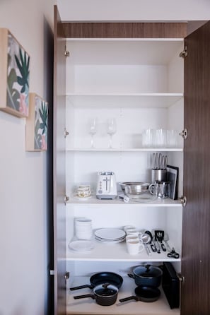 Eine Küchenschrank mit Regalen, voll mit Geschirr, Tassen, einem Toaster und Küchenutensilien.