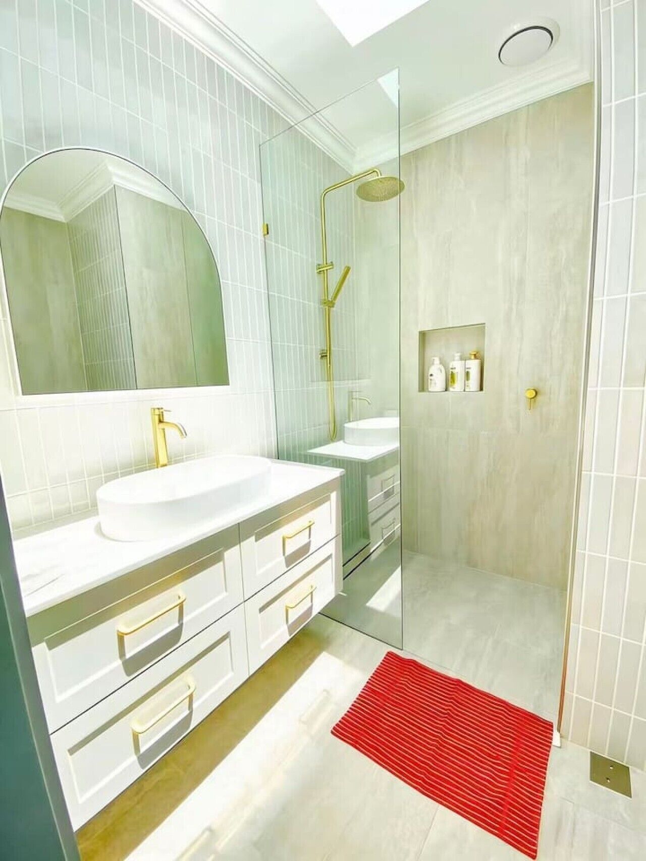 A modern bathroom with a large mirror, white vanity, and a glass-enclosed shower area.