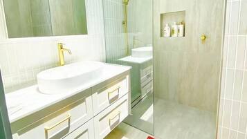 A modern bathroom with a large mirror, white vanity, and a glass-enclosed shower area.