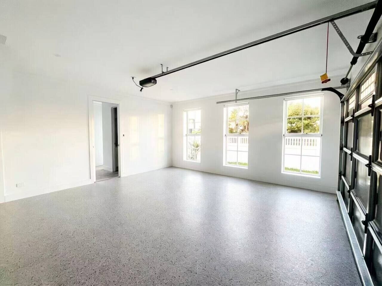 A spacious room with a high ceiling, large windows, and a garage door.