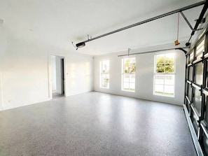 Amplia habitación con techo alto, ventanas grandes y una puerta de garaje.