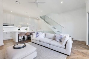 Ein modernes Interieur mit Sofa, Hocker, Küche und Treppe.