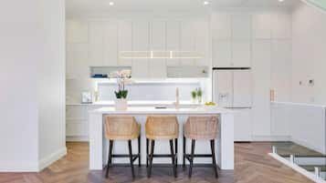 A modern kitchen with a central island, white cabinetry, and a herringbone wood floor.