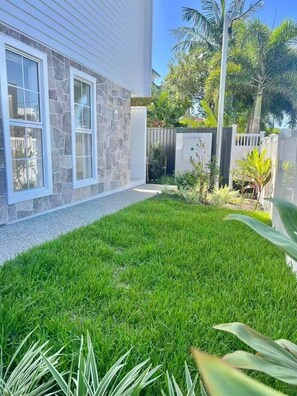 Una propiedad residencial con césped cuidado, fachada de piedra y patio trasero cercado.