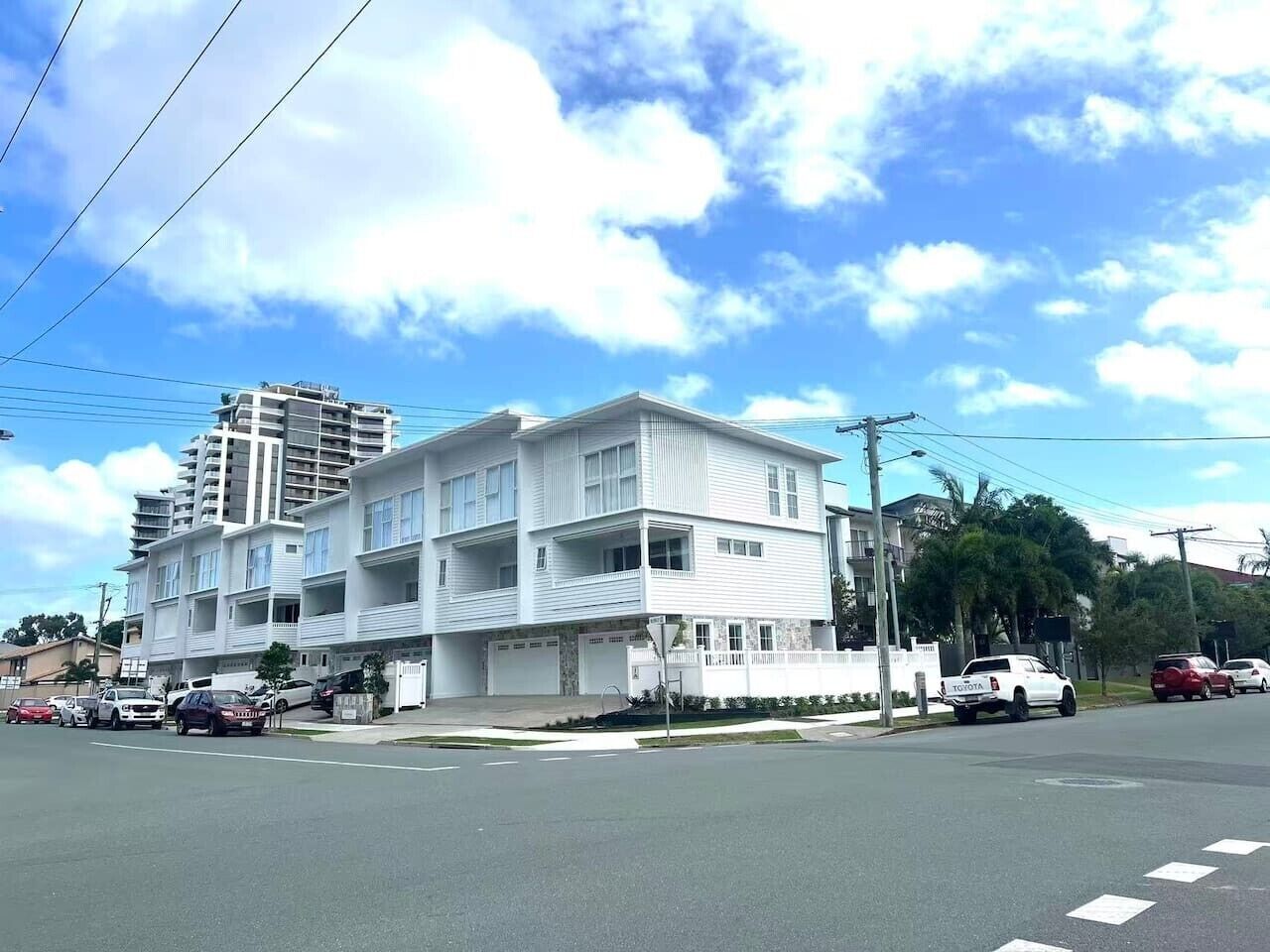 A multi-story residential building with a flat roof, multiple balconies, and a garage.