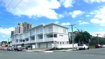 A multi-story residential building with a flat roof, multiple balconies, and a garage.