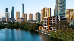Linha do horizonte da cidade com edifícios altos e um corpo de água em primeiro plano.