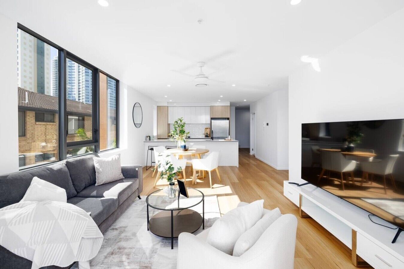 Eine moderne Wohnung mit Wohnzimmer, Essbereich, Küche und einem großen Fernseher.