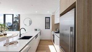 Uma cozinha moderna com uma ilha central, eletrodomésticos de aço inoxidável e vista pela janela.